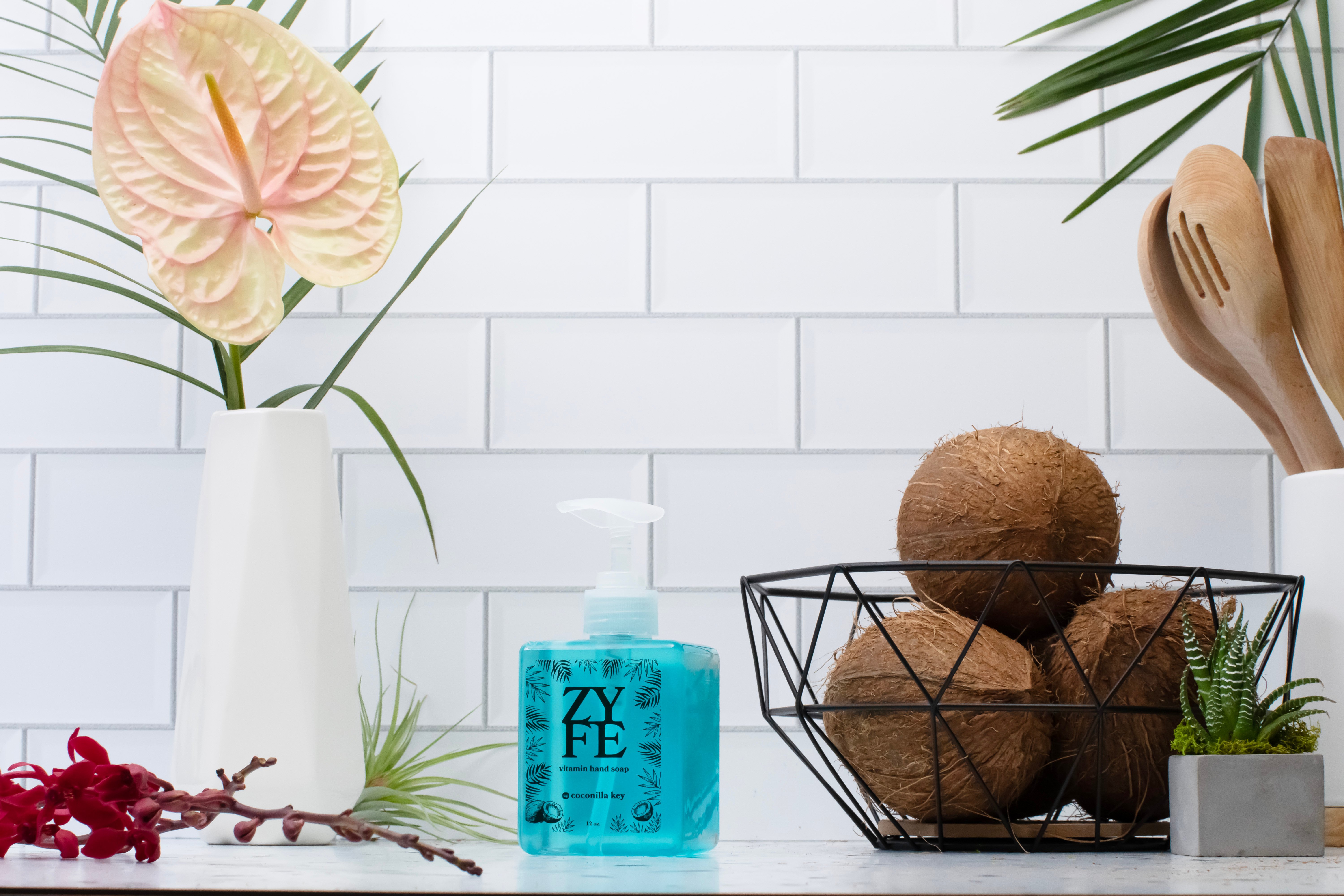 Bottle of zyfe coconilla key on kitchen counter next to a basket of coconuts and tropical plants