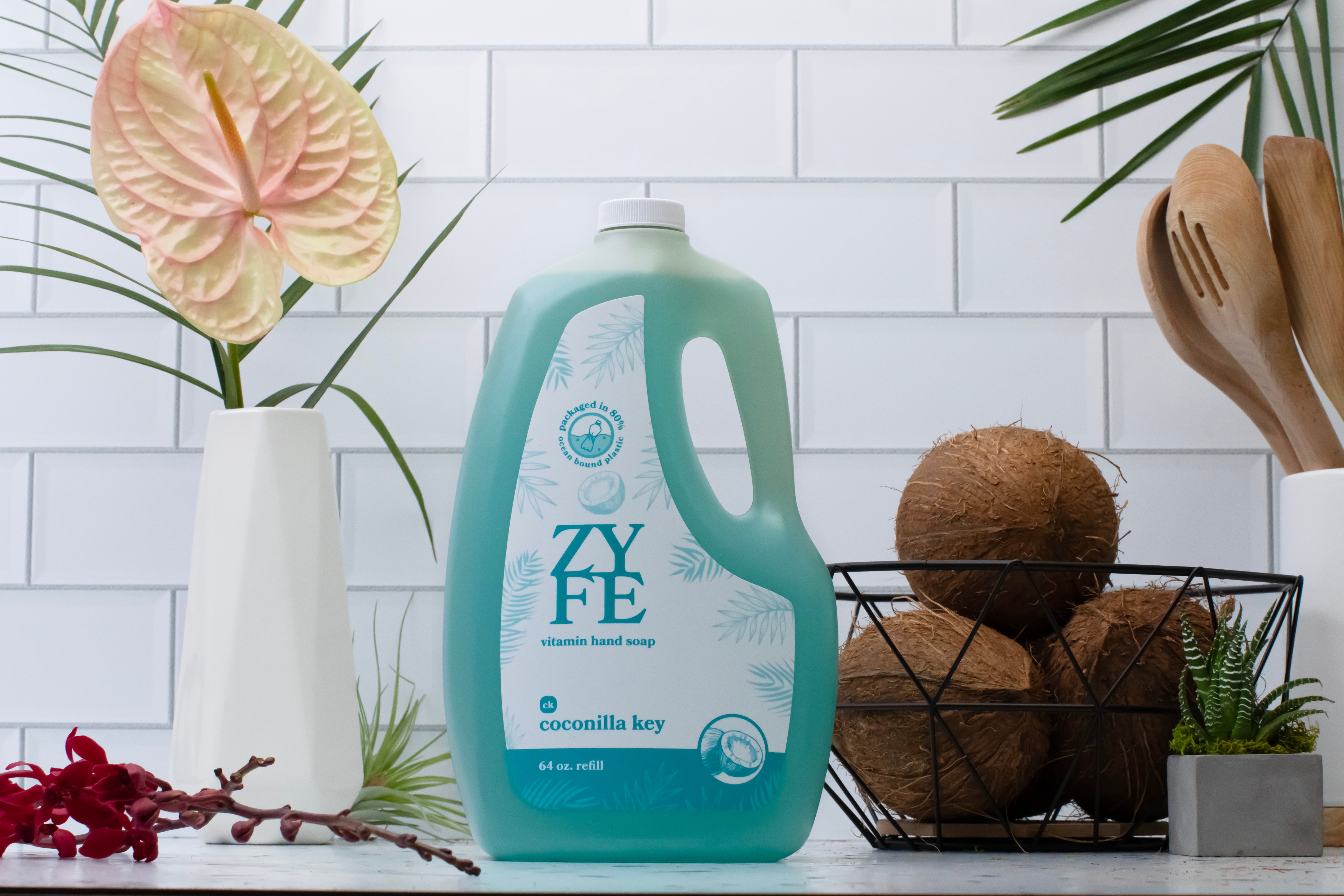 64oz bottle of coconilla key on kitchen counter next to a basket of coconuts and tropical plants.