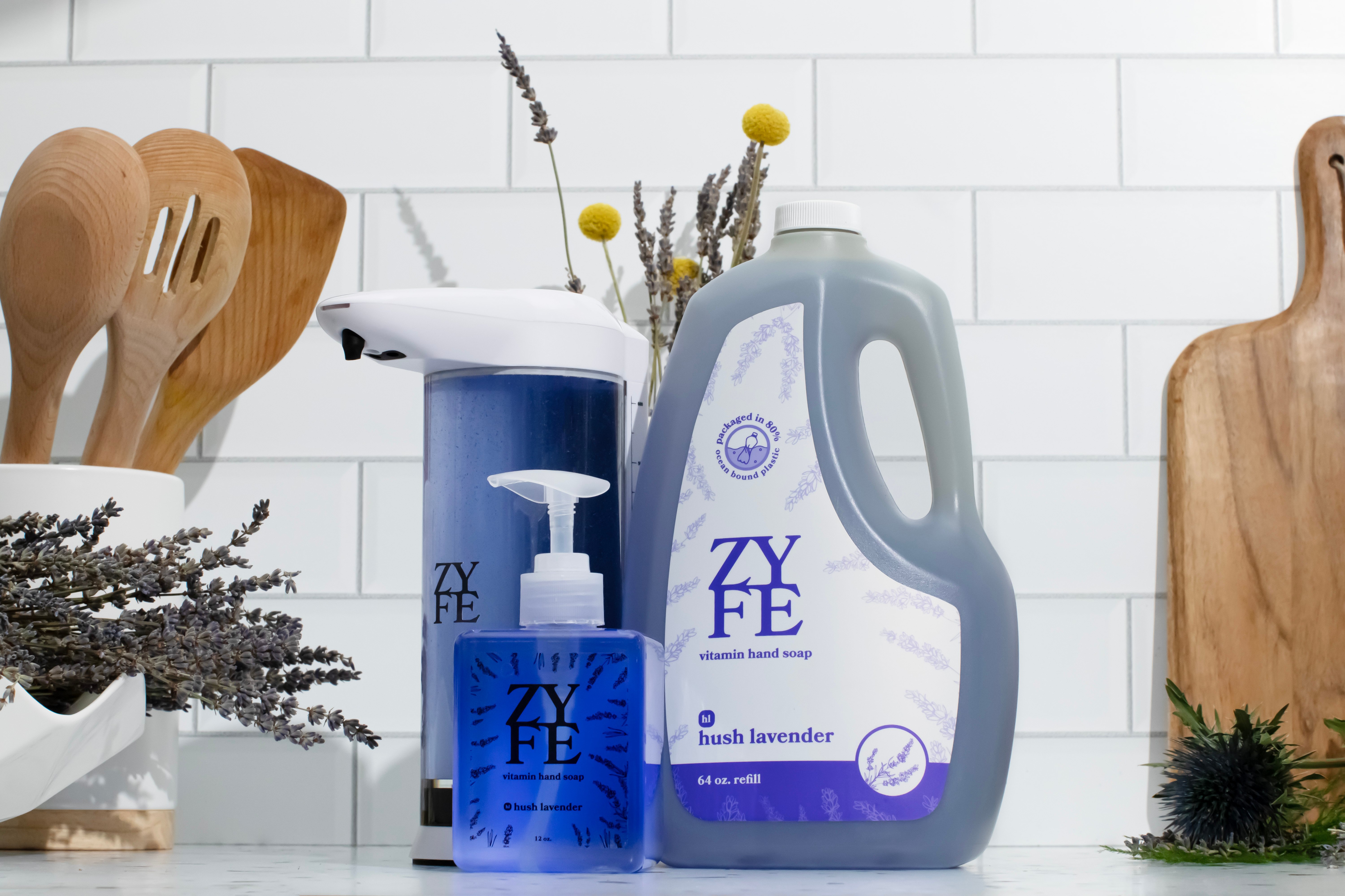 image of zyfe soap hush lavender 12oz and 64oz bottles, and a dock soap dispenser, grouped together on a kitchen counter