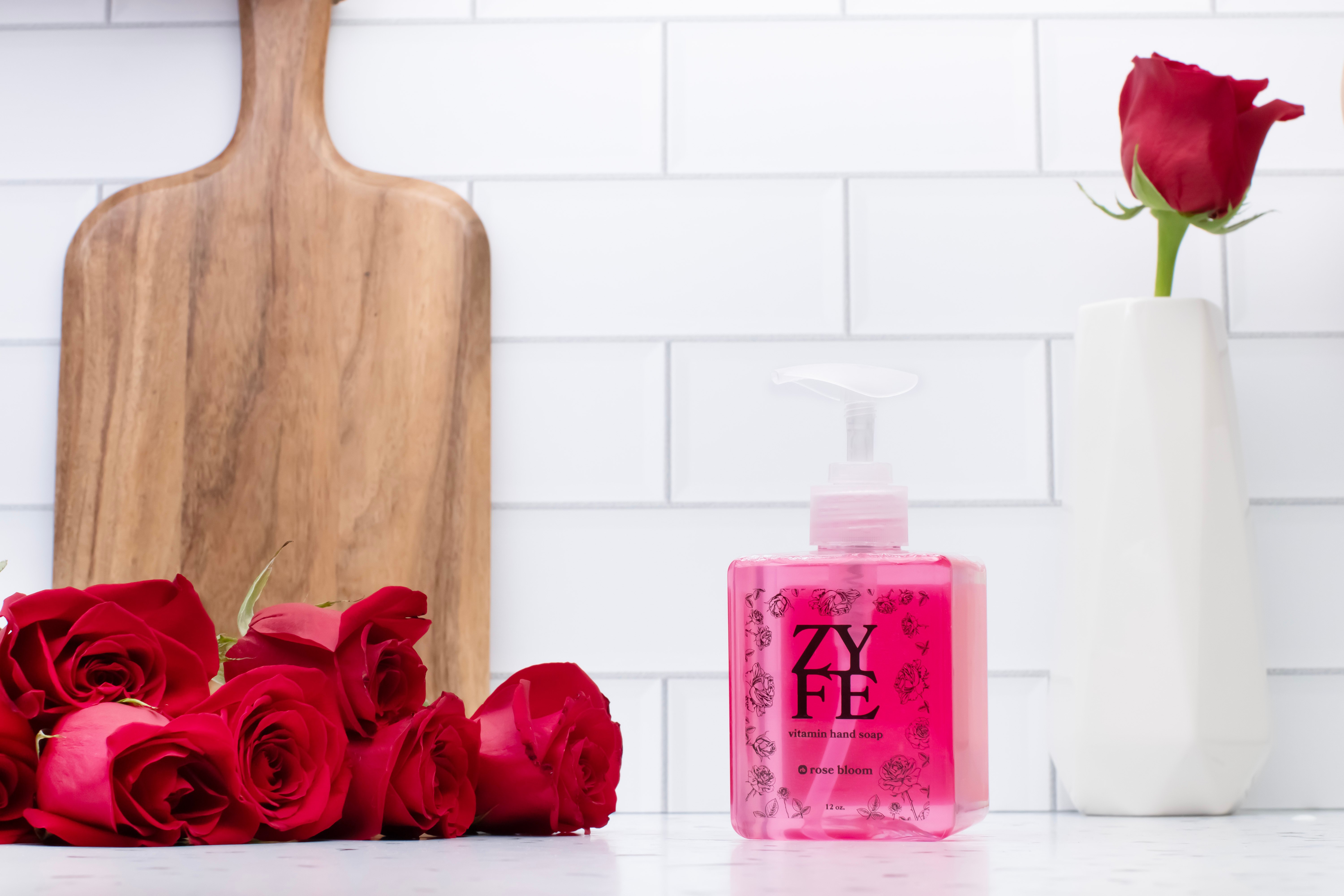 12oz bottle of rose bloom on kitchen counter surrounded by red roses